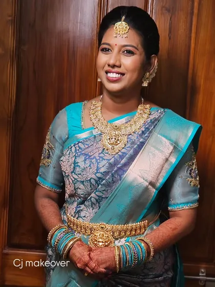 A smiling bride in a beautiful blue silk saree. The makeup is kept simple and elegant, with a focus on her happy expression.