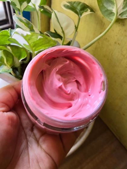 Holding a pot of the Rose Calamine pack to show its rich, creamy consistency.