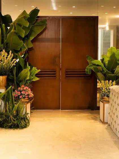 The entrance to the 'Shrimant', filled with auspicious banana trees, traditional brass vases, and fresh flowers, creating a warm and welcoming passage for guests.