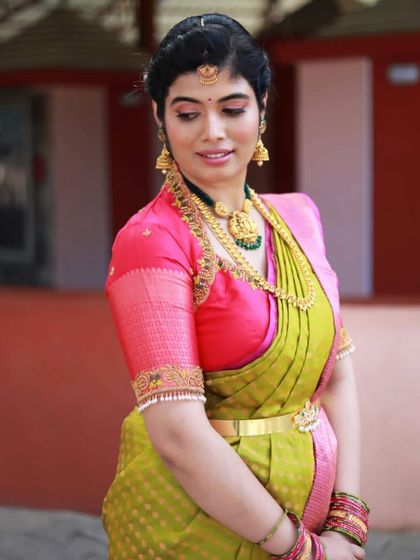 A side profile showcasing the elegant updo and the flawless finish of the makeup. The look is perfect for a traditional event like a naming ceremony.