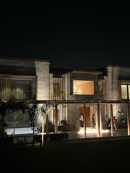 The illuminated facade of the farmhouse at night. The lighting strategy was designed to accentuate the building's strong horizontal and vertical lines, creating an elegant and inviting atmosphere.