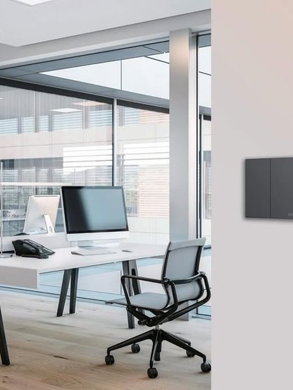 The brand new ABB KNX keypad with a digital thermostat, shown in a modern office setting. Its digital labeling changes color on activation, combining beauty with function.
