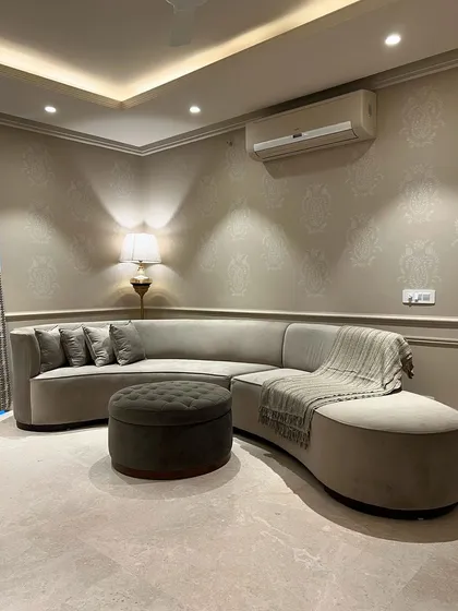 This view shows how the curved L-shaped sofa elegantly fits into the corner, maximizing seating while maintaining a soft, flowing aesthetic. The warm lighting enhances the room's inviting feel.