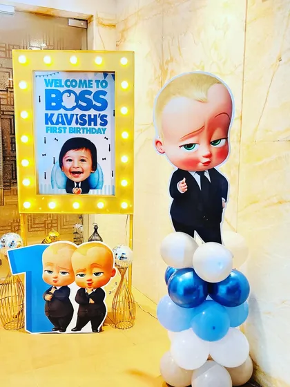 A personalized welcome area for a Boss Baby first birthday, featuring a light-up photo frame and character cutouts.