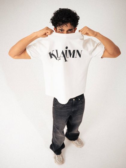 A high-angle shot where the model uses the t-shirt to partially cover his face. This focuses attention on the brand's logo, making it a clever and effective product shot.