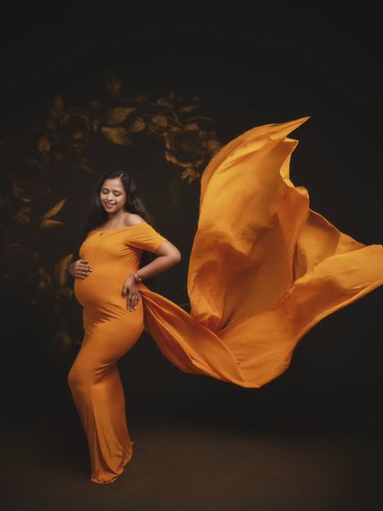 Some frames tell a story without words. This serene portrait in a flowing orange-gold gown was designed to bring out the beauty of motherhood.
