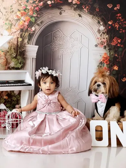 The birthday girl is joined by her furry friend, a well-dressed dog, for her piano-themed first birthday portrait.