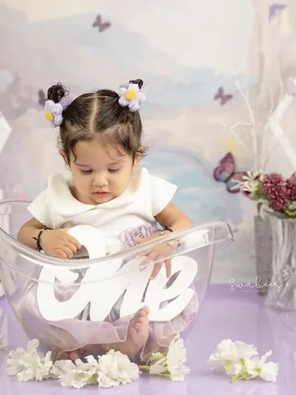 Holding the "one" sign in her tub, this little girl is celebrating her first birthday in a unique and adorable way.