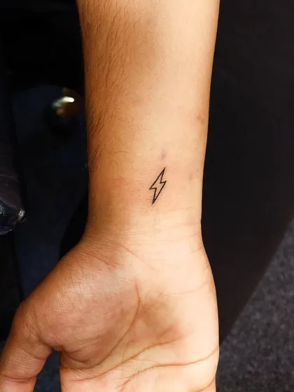 A tiny lightning bolt on the wrist. This super-clean, single-line tattoo is a symbol of power and a spark of energy in a minimalist form.