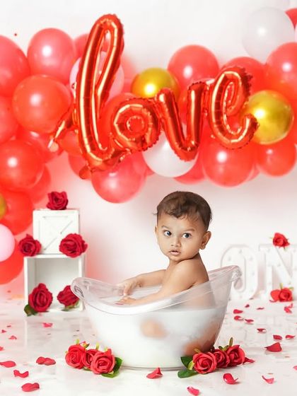A curious look from our little valentine in his rose-petal bath. The bright red balloons and flowers make for a striking and memorable photo.