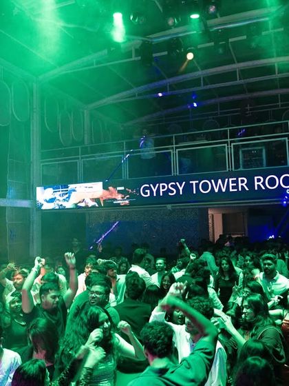 The green-lit dancefloor at Gypsy Tower Rooftop, packed with people ready to party.