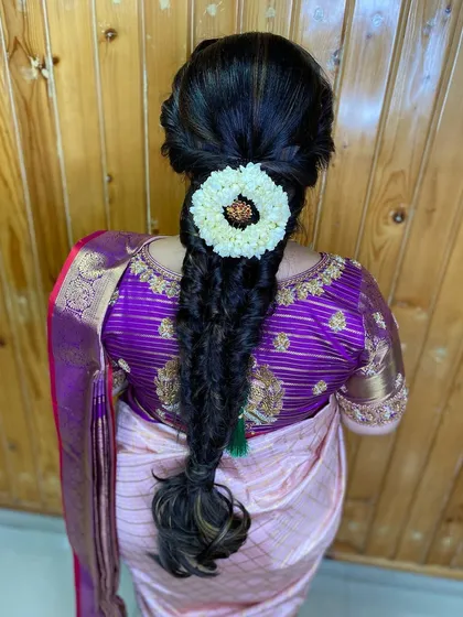 A messy braid with a jasmine and gold accessory, perfect for an engagement or pre-wedding event. The textured style is modern and chic.
