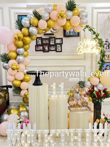 A lovely at-home setup with a gold, silver, and peach balloon arch. The decorations are integrated with the home's existing photo frames for a personal touch.