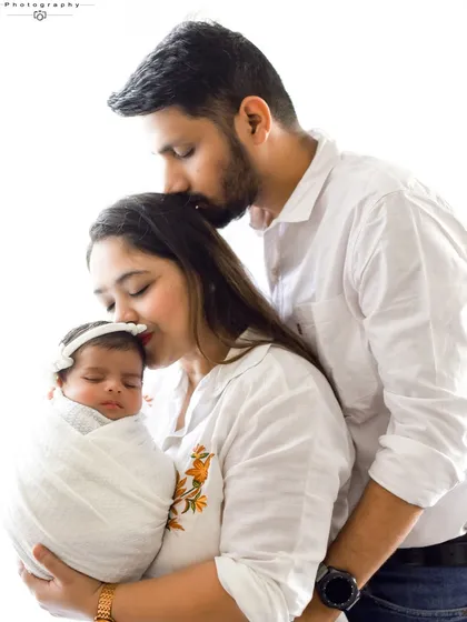 A close-up of a mother and father cherishing their sleeping newborn. The soft, natural light from the window gives this image a gentle and serene quality.