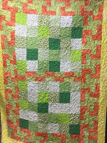 A full view of the green and orange quilt.