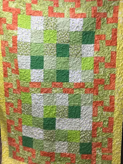 A full view of the green and orange quilt.