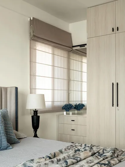 This shot emphasizes the functionality of the bedroom layout, with a tall wardrobe and adjacent chest of drawers providing varied storage options. The vertical channel-tufted headboard adds a touch of modern texture.