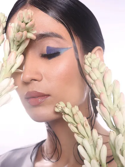 A serene portrait where the closed eyes draw full attention to the artistic and precise application of the blue liner.