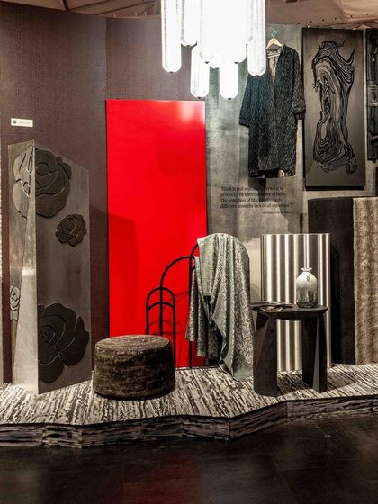 A curated corner of the 'Gothilicious' installation, where a bold red panel contrasts with dark, textured objects. The space is designed to be absorbing and moody, using scarred surfaces and evocative finishes to explore complex emotions.