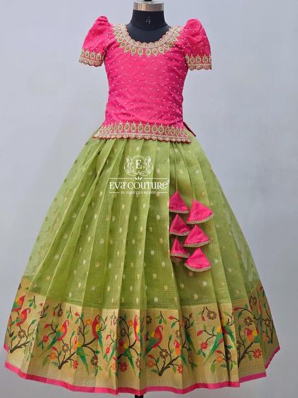 A bright pink and green lehenga. The skirt has a Paithani-style border with woven parrot motifs.