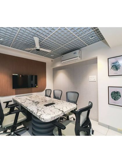 Our conference room, where ideas come to life. The space is equipped for presentations and features a stunning marble-topped table and a unique grid-patterned ceiling.