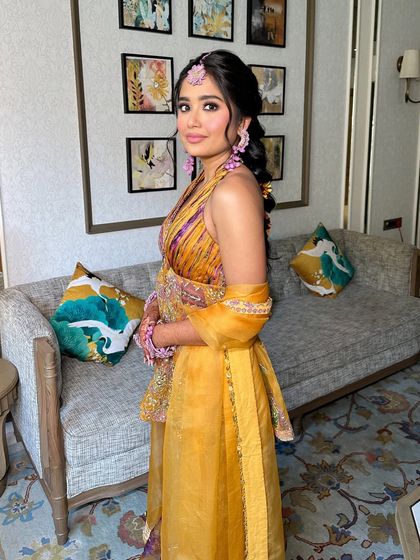 The side profile of the bride with her vibrant Haldi braid. The hairstyle is pulled away from her face to show off her floral jewelry and happy glow.