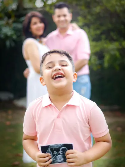The pure excitement of a boy about to become a big brother, with his parents looking on with so much love. This is a pregnancy announcement filled with genuine, heartfelt emotion.