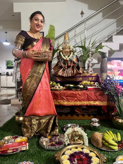 Another happy client celebrating the festival at home. She is draped in a lovely peach and black Kanchipuram silk, holding a basket of offerings.