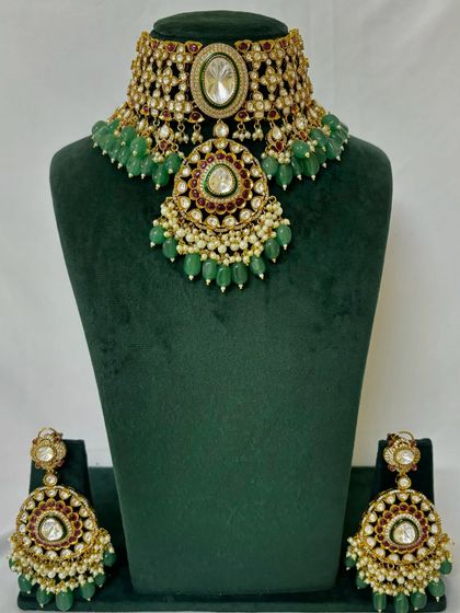 A full view of a heavy bridal choker with a large pendant and green bead drops. This rental set comes with matching oversized earrings.