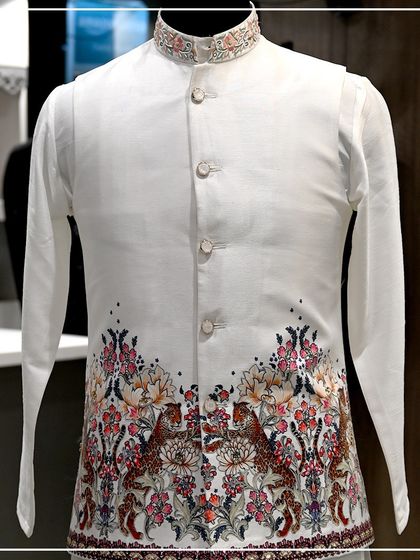 A white Nehru jacket with a beautiful, colorful print of tigers and flowers along the bottom. This is a unique and artistic piece for a festive occasion.