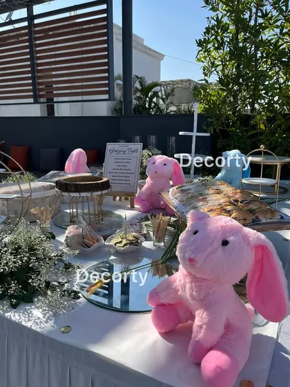 A grazing table set up for a baby shower, decorated with plush bunnies and other themed elements.
