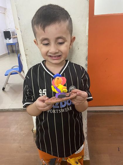 A young boy looks proudly at the colorful Ganesha figurine he made in our class.