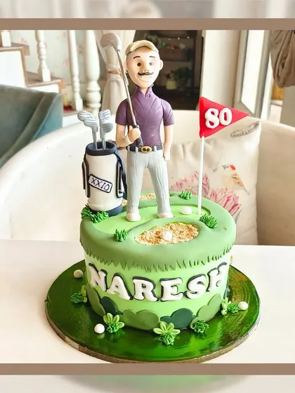 A perfect cake for a golf lover's 80th birthday, featuring a fondant figure on a green with a golf bag and flag.