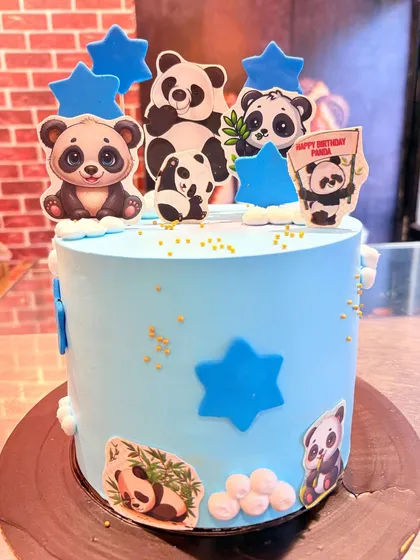 A cute panda-themed cake in a lovely shade of blue. The cake is decorated with multiple panda cutouts and blue stars, making it a fun choice for a panda lover.