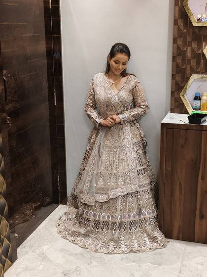A client posing in a beautiful tiered lehenga with intricate embroidery.