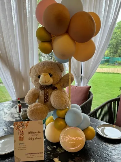 A teddy bear centerpiece at a table, complete with a card detailing the activities for the baby shower, ensuring guests know what to expect.