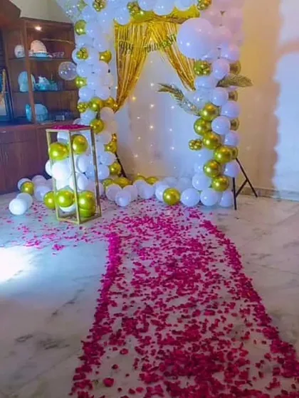 Another view of the rose petal pathway and the elegant white and gold balloon arch, perfect for a home anniversary celebration.