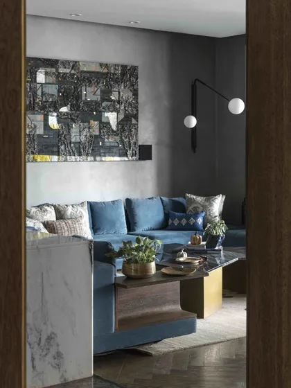 A glimpse into the family lounge, showing a large abstract artwork by Kaushik Saha. The deep blue sofa and dark wood tones create a sophisticated yet comfortable atmosphere.