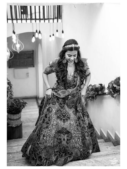 A beautiful black and white shot of the bride descending the stairs, her intricate lehenga on full display.