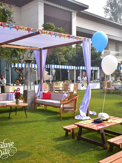A wide view of a 'Transformers' themed birthday party, with picnic tables and lounge areas set up on the lawn.