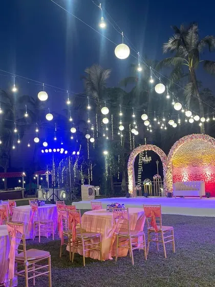 A beautiful stage setup with three floral arches and hanging chandeliers. The warm lighting and pastel colors create a romantic and inviting focal point for the evening.