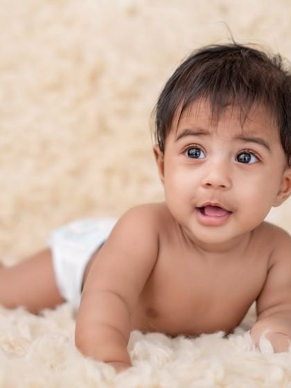 A baby boy lying on a soft, fluffy rug.