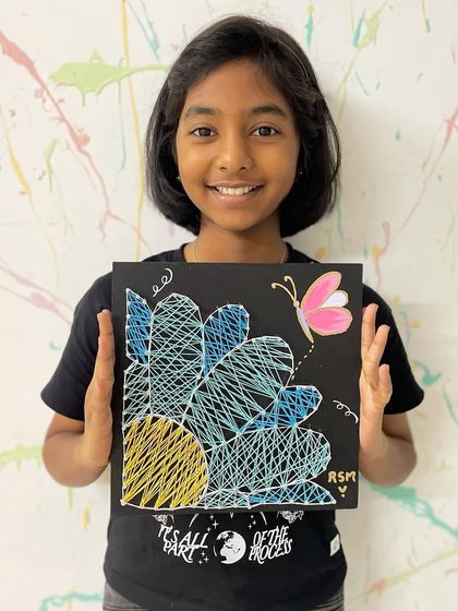 The beautiful final result. A string art flower with a delicate butterfly, proudly displayed by its young creator.