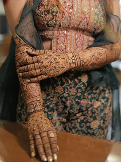 The bride's intricate mehendi is a work of art that complements her stunning bridal outfit.