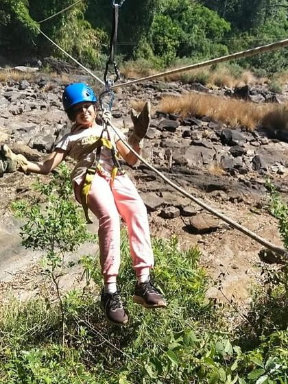A participant smiles as she glides across the rope bridge, enjoying the adventure.