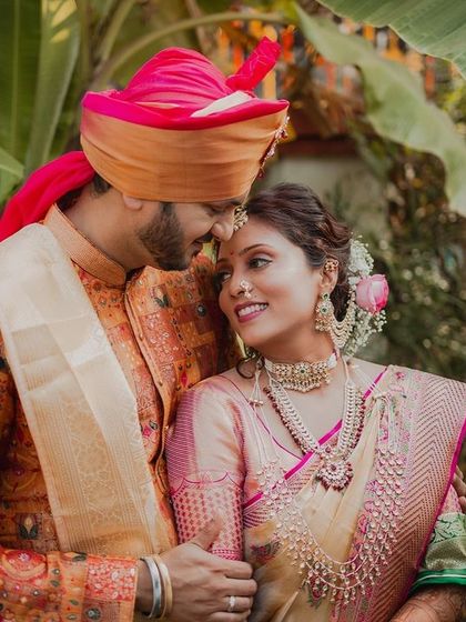 The loving gaze between a Maharashtrian couple, framed by lush banana leaves. The groom's vibrant pheta and the bride's traditional jewelry complete this picture of cultural elegance and affection.