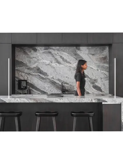 A wider view of the kitchen and bar, showcasing the dark wood cabinetry that provides a beautiful contrast to the veined stone.