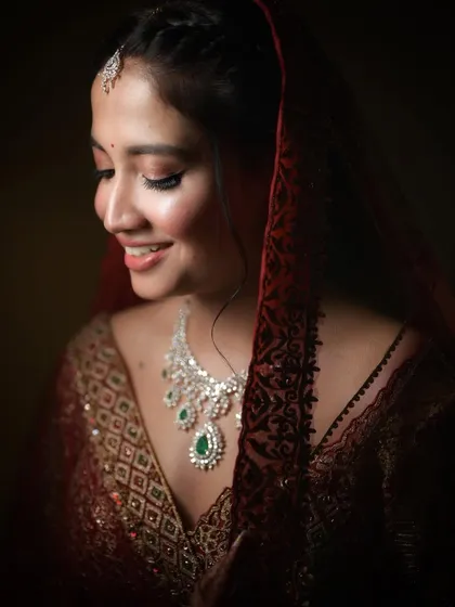 A close-up of the same bride, this time with a soft smile. This portrait showcases her beautiful jewelry and the delicate details of her wedding attire under soft, flattering light.