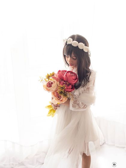 A soft and dreamy portrait with high-key lighting. The floral crown and bouquet give her an angelic look.