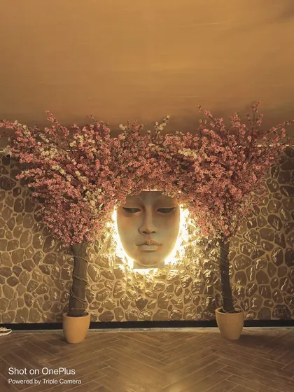 Another view of the cherry blossom and sculpture installation, highlighting the warm, ambient lighting.